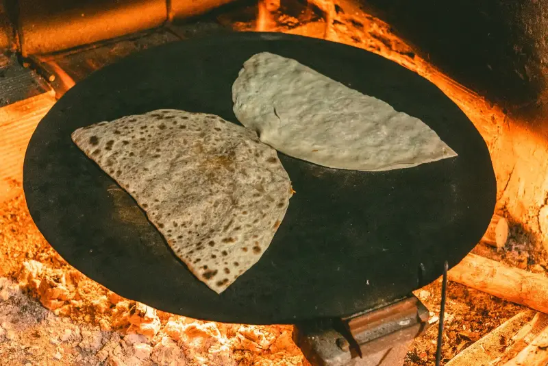 Odun ateşinin üzerindeki sacda pişen iki yufka ekmeği